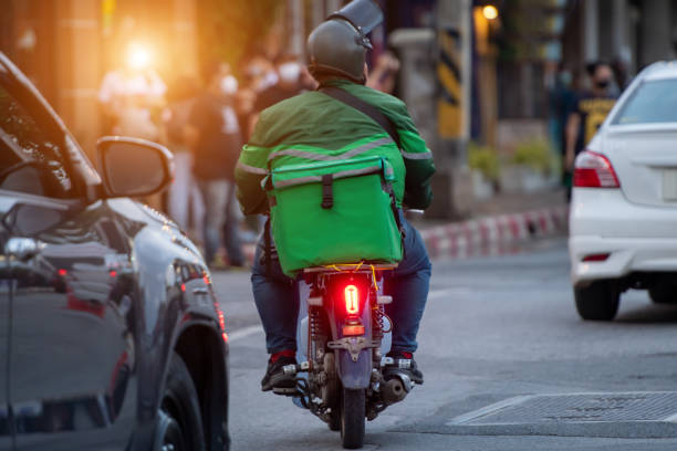 Seorang kurir berjaket hijau mengantar paket dengan motor.